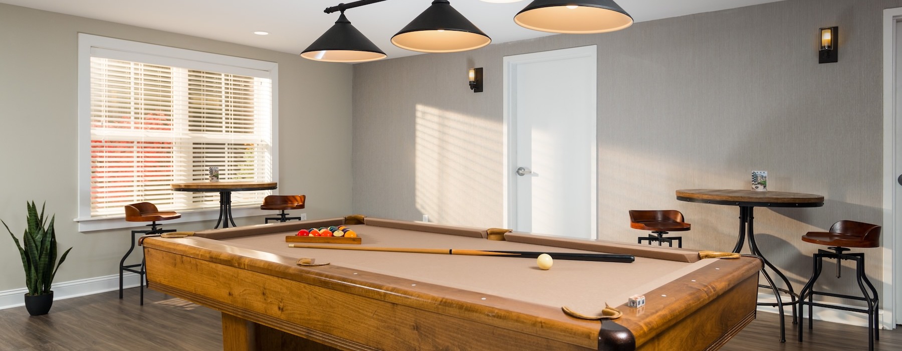a room with a pool table, large window and chairs and tables
