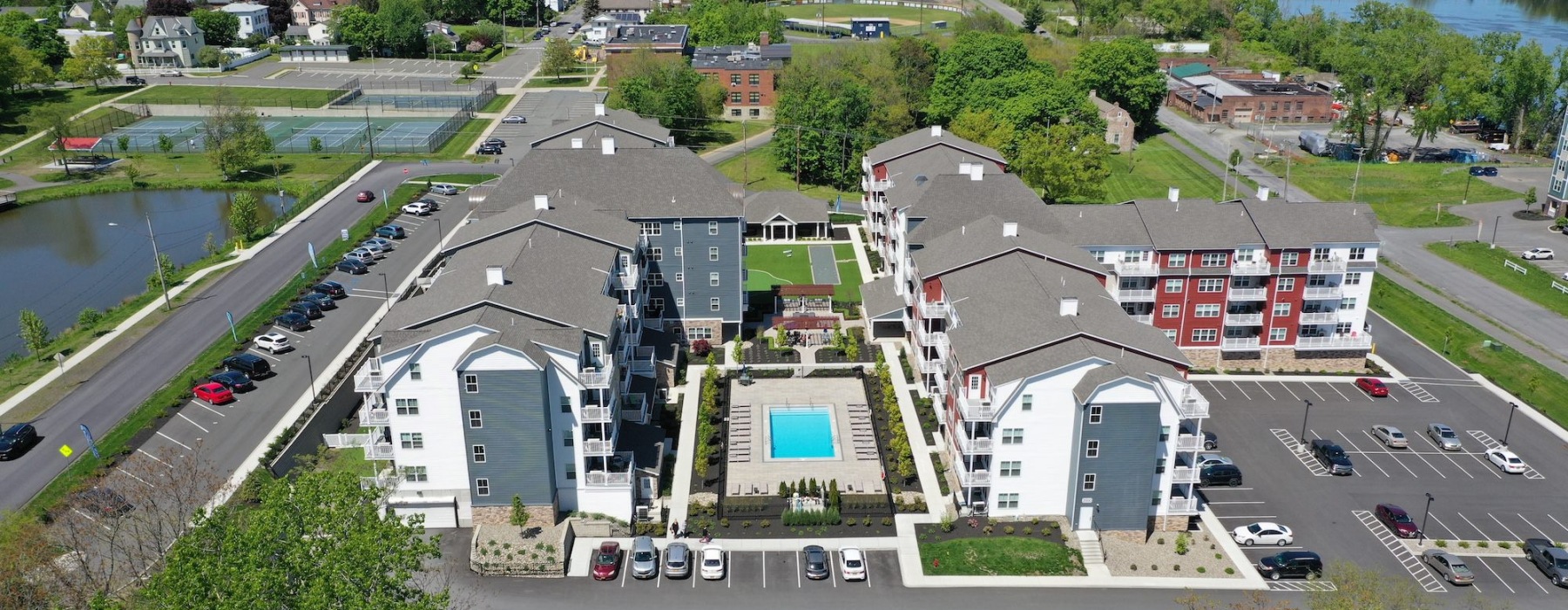 aerial view of pool and building with a parking lot